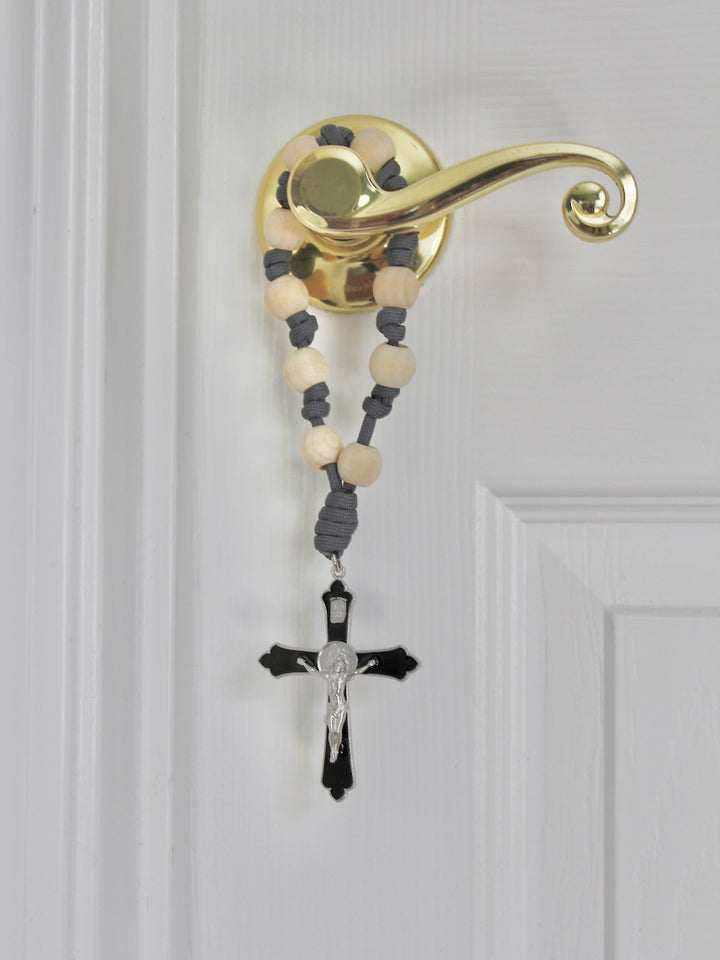 St. Michael Faithful Defender Door Rosary hanging on a brass door handle with natural wood beads and gray cord