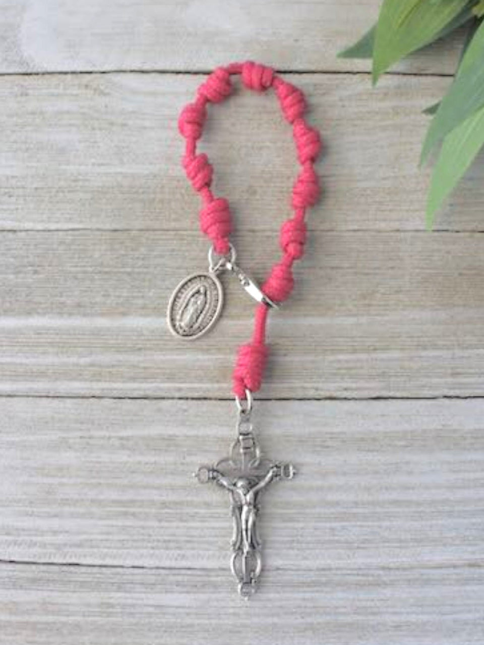 Pink rosary with silver crucifix and medal on a wooden surface
