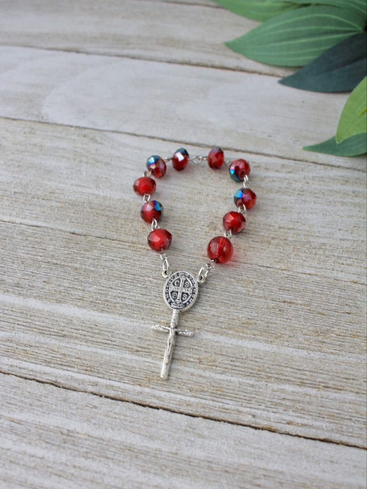 Red beaded rosary with silver clasp on a wooden surface
