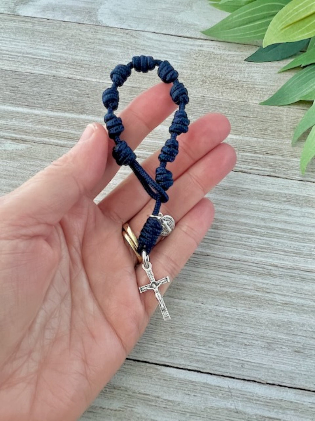 Navy blue one-decade Catholic pocket rosary with knotted cord, silver-tone cross and medal, handmade by Knots of Grace, in woman's hand