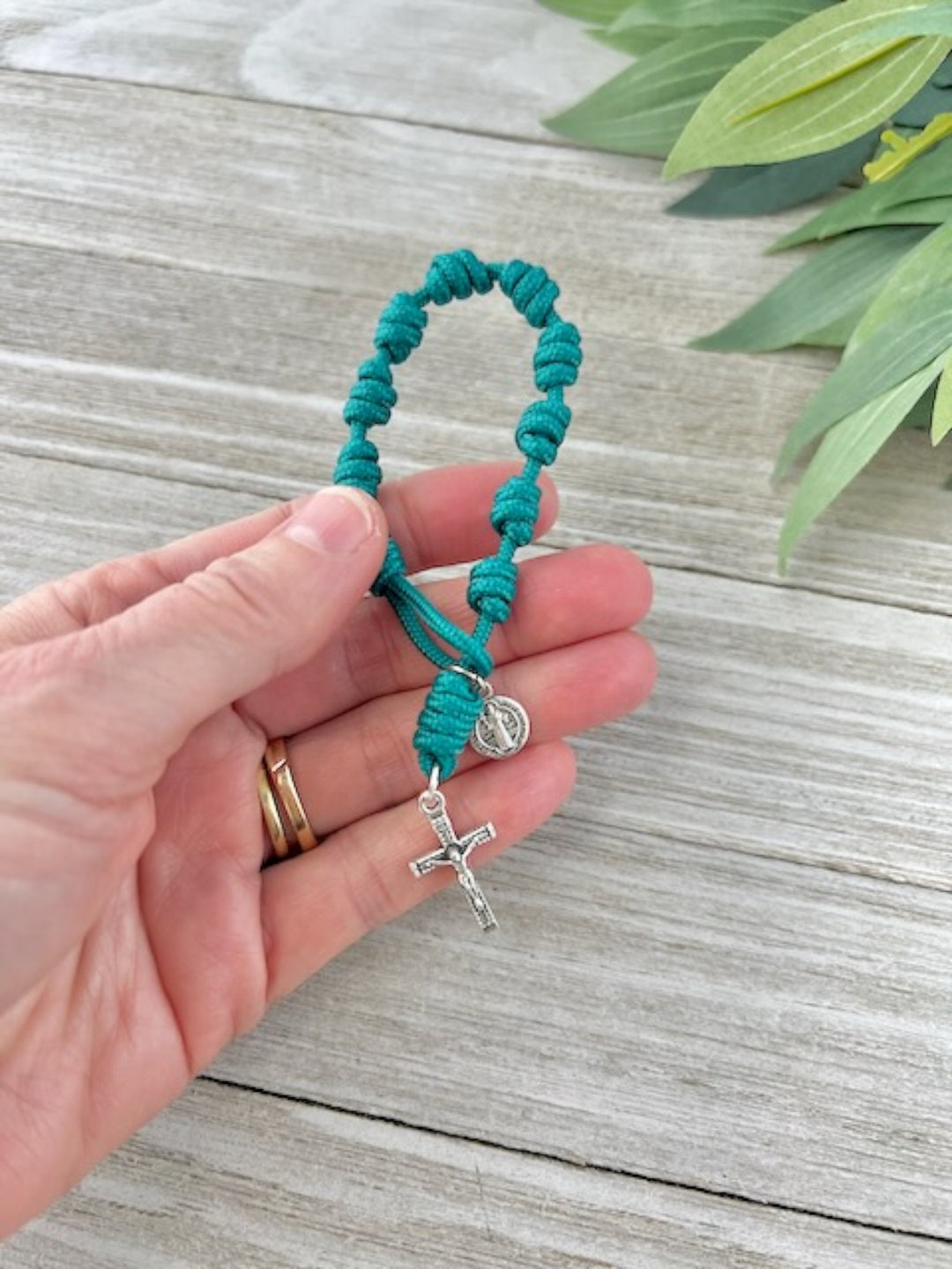 Teal one-decade Catholic pocket rosary with knotted cord, silver-tone cross and medal, handmade by Knots of Grace, in woman's hand