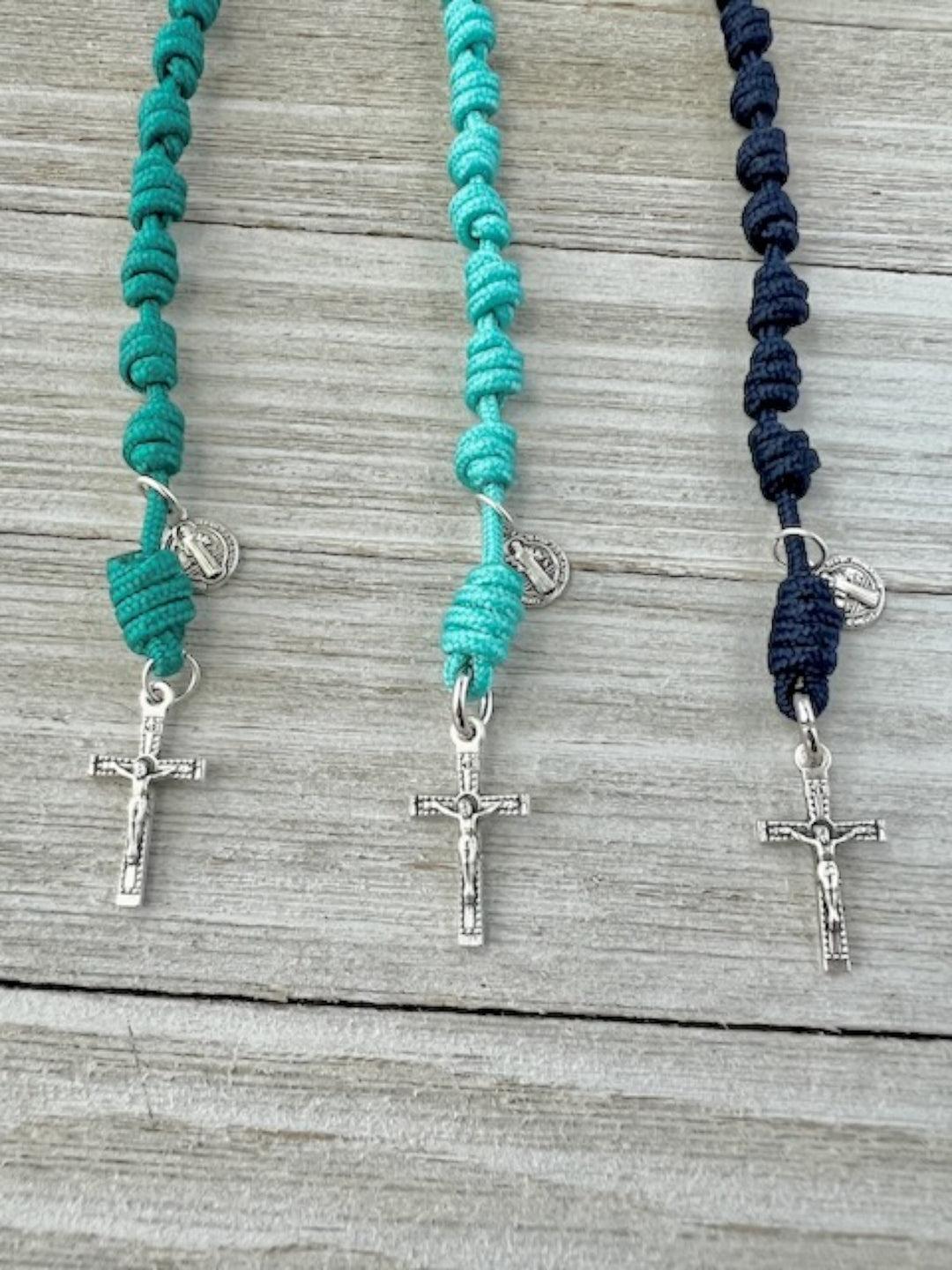 Close-up of Knots of Grace handmade one-decade Tiny Traveler pocket rosaries in teal, turquoise, and navy cord